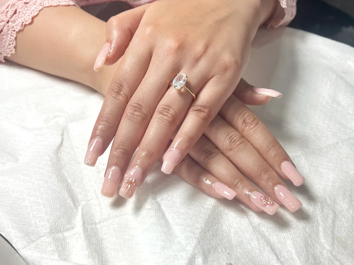 Glossy soft pink acrylic nails with delicate nail art at Morning Glory Beauty Clinic in Jhelum.