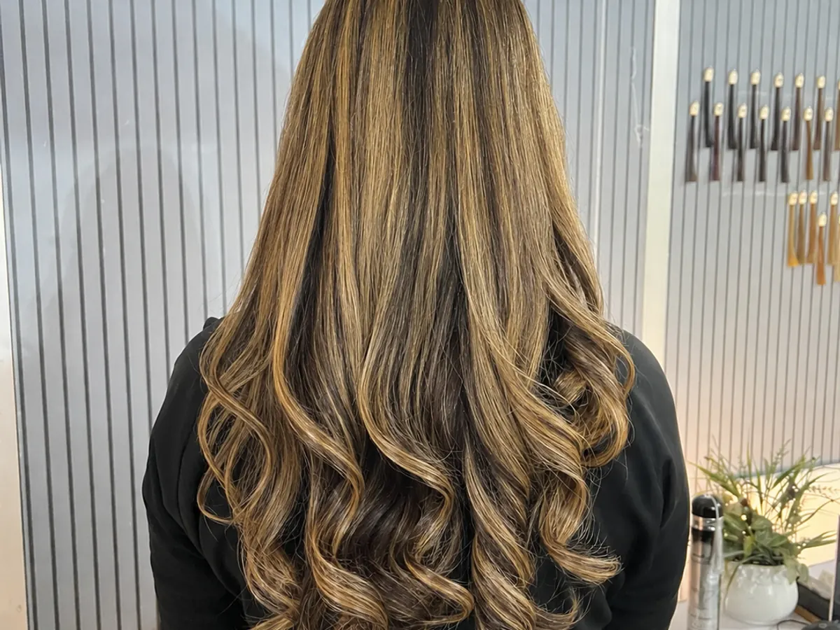 Dimensional blonde hair highlights styled in loose curls at Morning Glory Beauty Clinic in Jhelum.